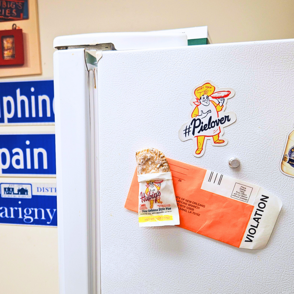 Fridge with various Hubig's Pies magnets holding a New Orleans parking ticket.