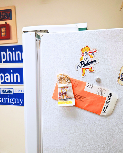Fridge with various Hubig's Pies magnets holding a New Orleans parking ticket.